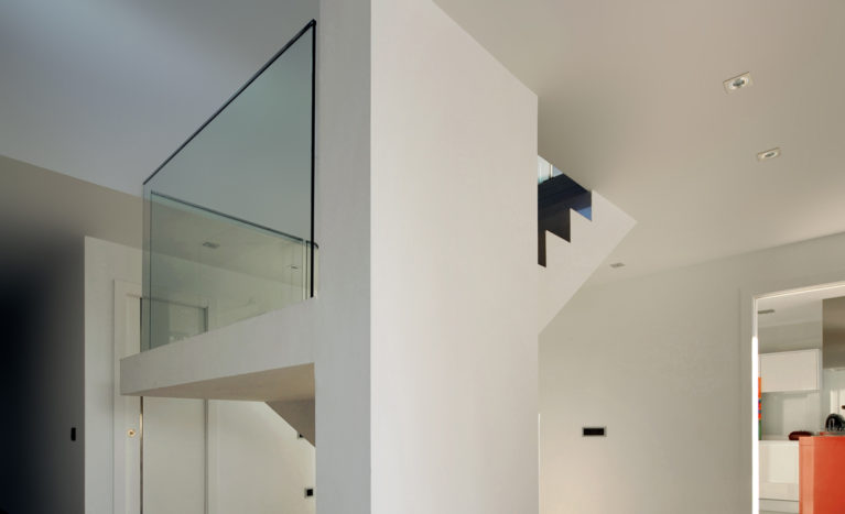 AQSO arquitectos office. Las escaleras ocupan un lugar central en el recibidor, son un elemento escultórico y minimalista con una barandilla de cristal.
