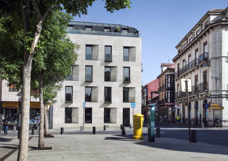 AQSO arquitectos office. La fachada principal del edificio residencial Maragato Lofts captura la luz del oeste a través de la plaza gracias a sus huecos abocinados y los balcones.