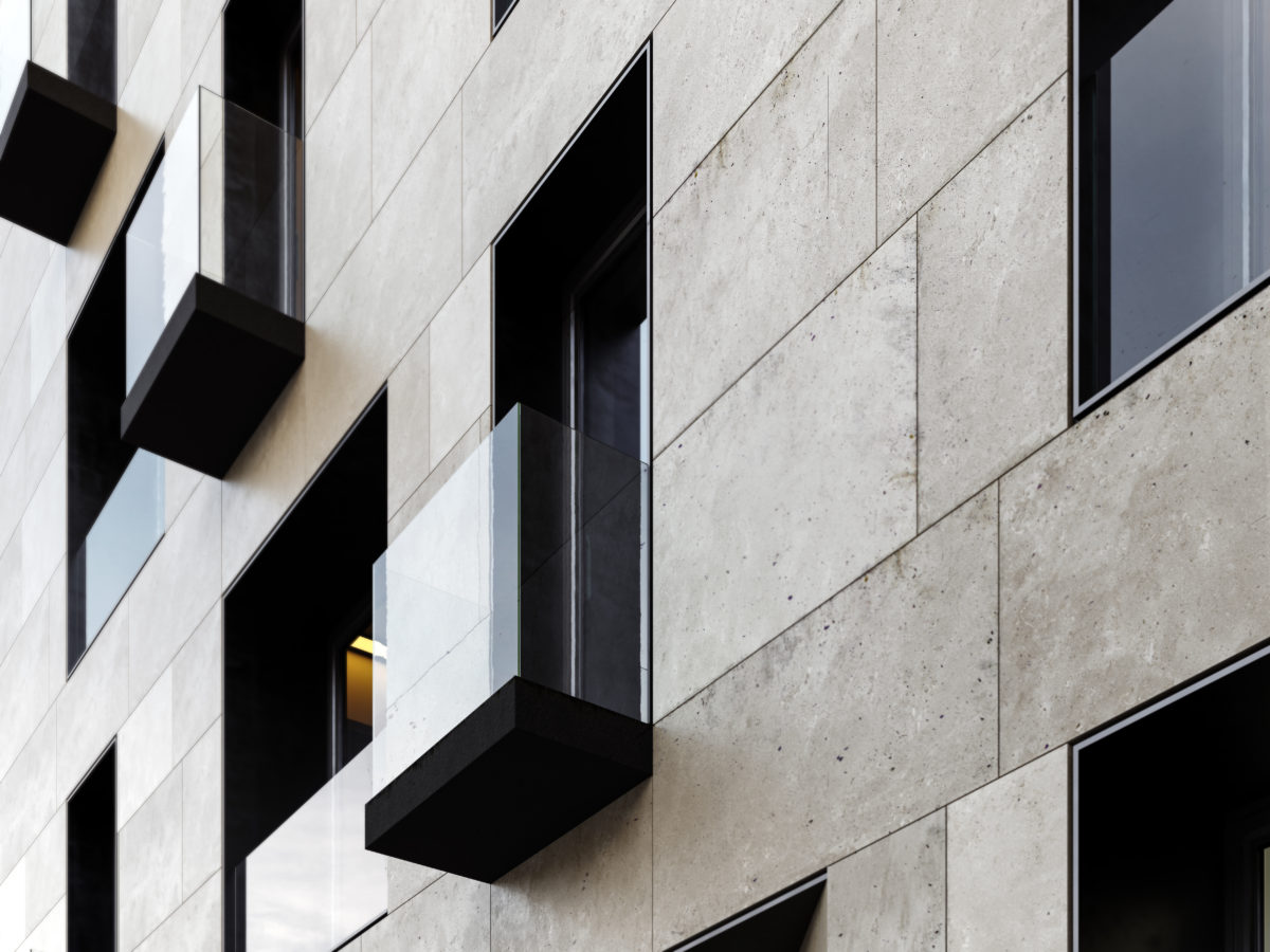 AQSO arquitectos office. Detail of one of the balconies. A simple slab cladded with dark metal protrudes from the facade plane with a frameless glass balustrade, contrasting with the limestone cladding.