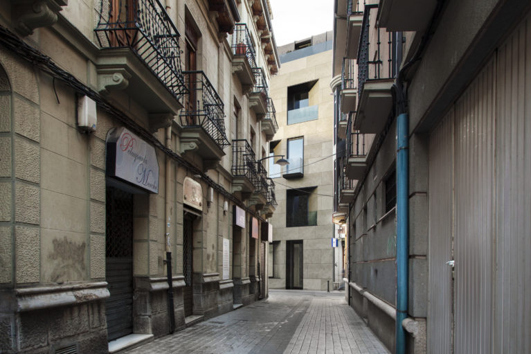 AQSO arquitectos office. El edificio, visto desde la estrecha calle adyacente, deja ver sus balcones y ventanas abocinadas que capturan las vistas del entorno urbano.