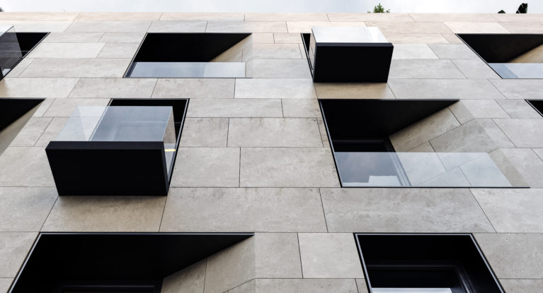 AQSO arquitectos office. The sober facade combines three materials: limestone, black metal and glass. The arrangements of the openings offers a dynamic look based on simple displacements, chamfered corners and alignments.