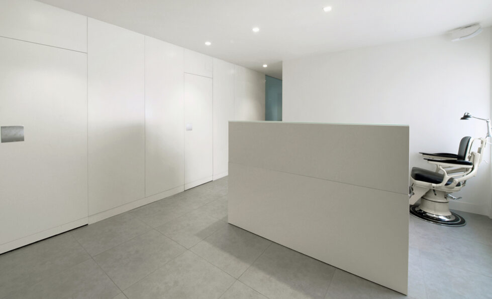 AQSO arquitectos office. The Zurbarán clinic has a white lacquered wooden counter in the dentist's consulting room. It is a simple and minimalist interior design in white.