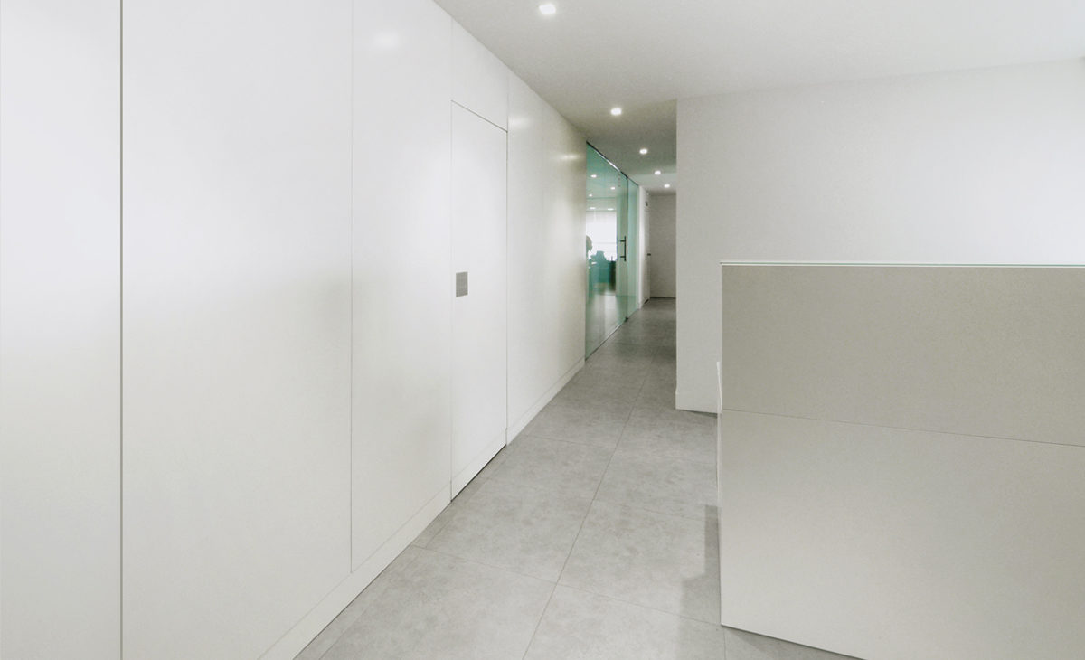 AQSO arquitectos office. Desde el vestíbulo de entrada de esta clínica de estilo mimimalista se accede a las consultas a través de un pasillo de paredes blancas.