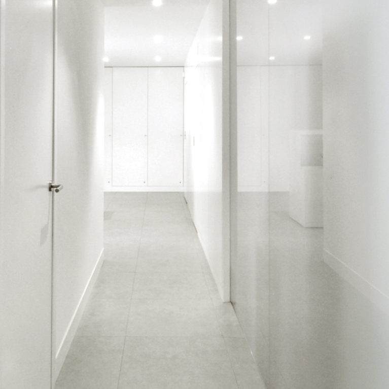 AQSO arquitectos office. The corridor of this health centre has white walls, translucent glass doors with stainless steel handles and glass partitions.