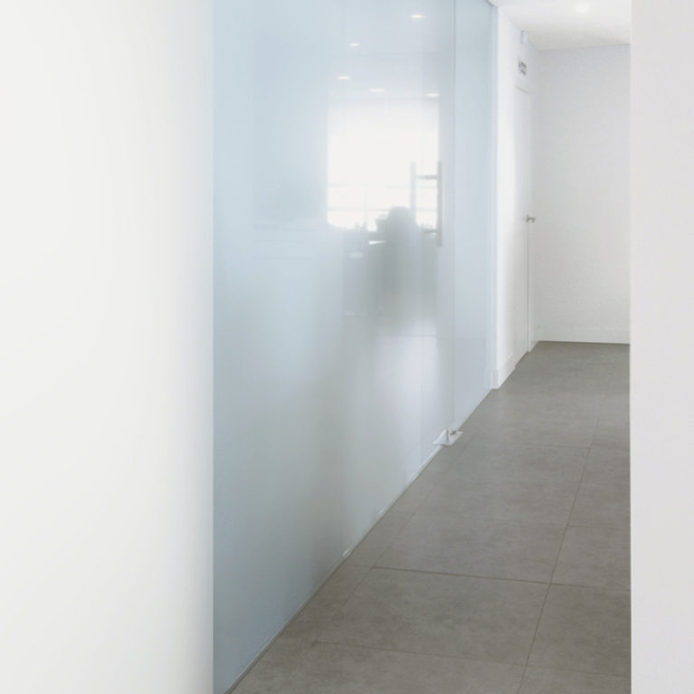 AQSO arquitectos office. Las particiones interiores de las consultas están hechas de cristal translúcido laminado, que da un aspecto lechoso y matiza la luz natural.