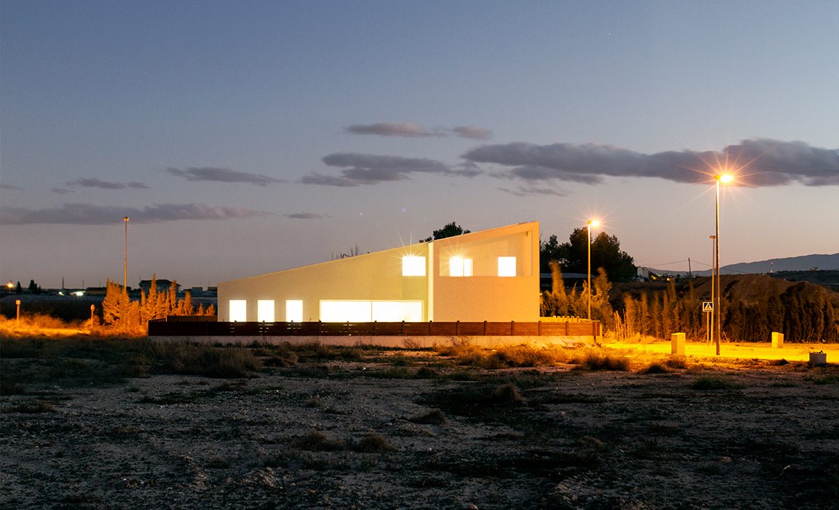 AQSO arquitectos office. The exterior view of the house, with the sloping roof, the white walls and the simple, modern silhouette that stands out against the landscape.
