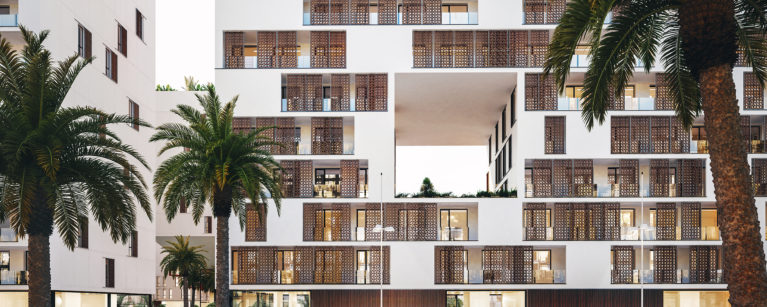 AQSO arquitectos office, residencial anfa. La vista frontal del alzado muestra los balcones con paneles correderos de tracería de madera inspirados en juegos geométricos marroquís, que forman una piel siempre cambiante..