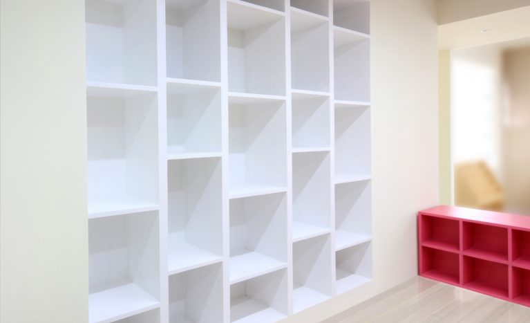 AQSO arquitectos office. The bespoke white wall-mounted bookcase has an original and functional design, with shelves at different heights, creating a rhythm of recesses.