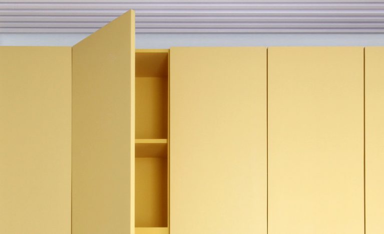 AQSO arquitectos office. Los muebles de este centro de gestión escolar están hechos de madera lacada de colores. Son unos armarios simples y funcionales con tiradores y bisagras ocultos.