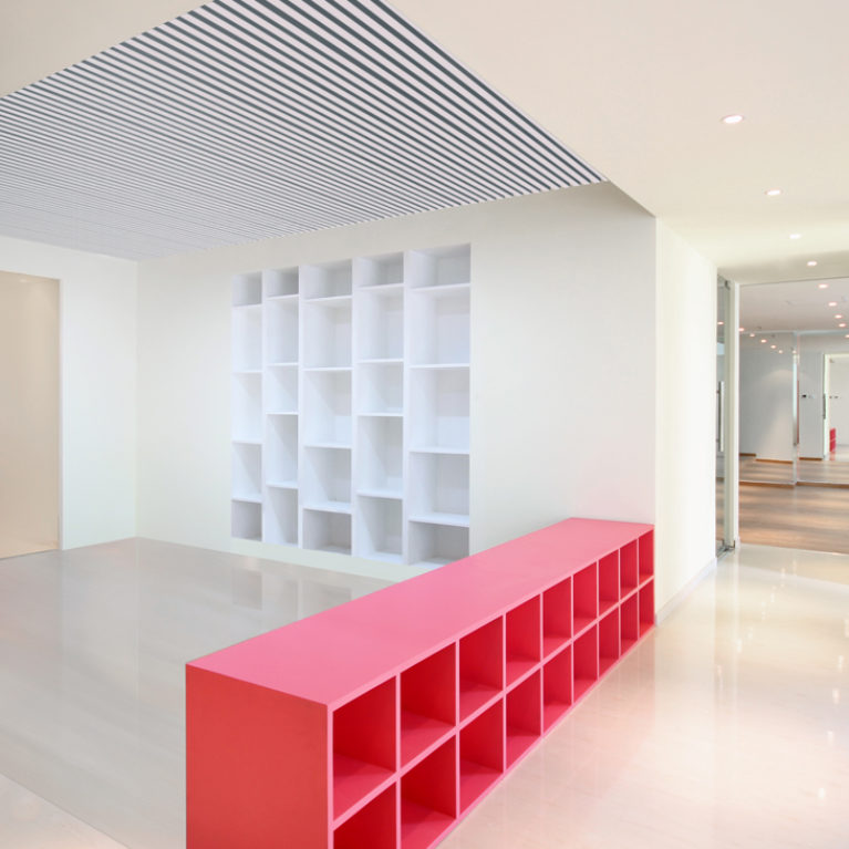 AQSO arquitectos office. In the central part of the premises is the workshop area, which has a low unit of pink lacquered wood and a shelving unit built into the wall.