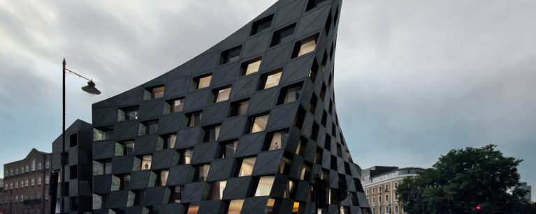 AQSO arquitectos office. La fachada paramétrica vista desde la calle ofrece la imagen diámica y cambiante de un edificio curvo de hormigón negro.